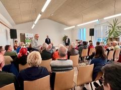 Blick in einem Raum mit Menschen auf Stühlen.