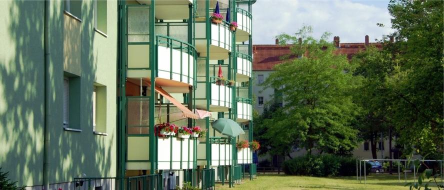 Wohngebiete mehrstöckiger Wohnblock mit Balkonen und einer Wiese mit Bäumen davor