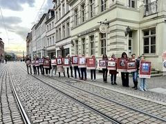 viele Menschen stehen in einer Reihe und halten Plakate hoch.