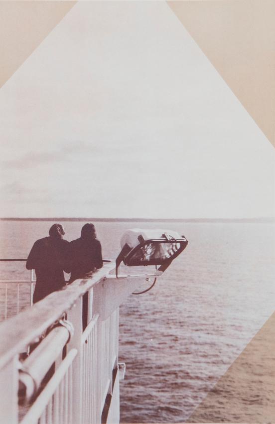 Foto einer Seebrücke mit zwei Personen, die aufs Meer schauen. Ein Lichtflutmast ist am Geländer der Seebrücke montiert.