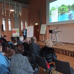 Auswertung des Welt-Cafés Eine Gruppe Menschen hört sich bei der Veranstaltung einen Beitrag zur Mobilität an