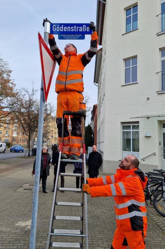 Bauhofmitarbeiter montieren das Schild zur Gödenstraße.