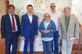 Gruppe von Personen im Rathauseinang vor dem Wappen der Stadt