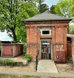 Altes Backsteingebäude entlang eines Gehweges mit der Überschrift Bücher-Trafo