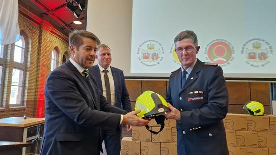 Übergabe der neuen Helme an Oliver Tröger, Sprecher der Freiwilligen Feuerwehren.