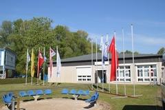 Vereinsheim "Propeller" Flaggenmasten stehen auf einer Rasenfläche vor einem Gebäude.