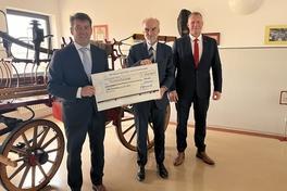 drei Personen mit einem großen Scheck in der Hand