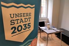 Banner des Leitbildes im Vordergrund, im Hintergrund ein Tisch mit Zetteln und Stiften