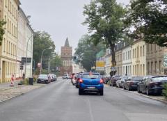 Mehrere Autos stehen an einer Ampel, im Hintergrund der Rathenower Torturm, links und rechts Häuserfronten