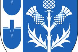 Das Wappen von Wust zeigt in einem blauen Schild eine silberne dreiköpfige Distel und in einer silbernen Flanke zwei blaue Spatenblätter.