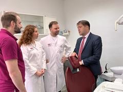 Vier Menschen in einem Behandlungsszimmer im Gespräch.