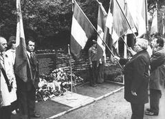 Zwangsarbeiter Personen die mit Fahnen an einem Grab stehen