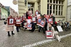 viele Menschen stehen in einer Gruppe und halten Plakate hoch.