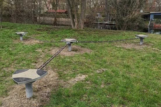 Spielgerät auf Rasenfläche: drei Slacklines gehen von einem Mittelpunkt aus in drei Richtungen, in der Mittel und an den Rändern sind Standfächen