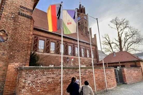 Drei Frauen laufen am rathaus vor Trauerbeflaggung