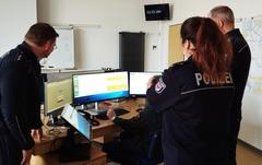 3 Polizisten stehen vor einem APC Arbeitsplatz.