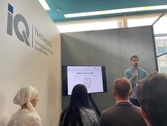 Hinterköpfe von vier Personen die einen Mann anschauen der gerade einen Vortrag hält.