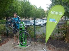 Ein Mann steht an der Reparatur-Station und hat sein Fahrrad darauf aufgehangen