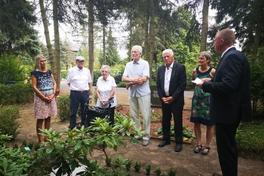 Personengruppe steht um ein Grab im Halbkreis