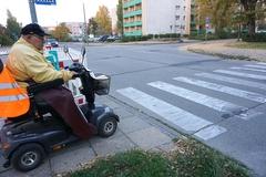 Rohlstuhlfahrer wartet vor Überweg