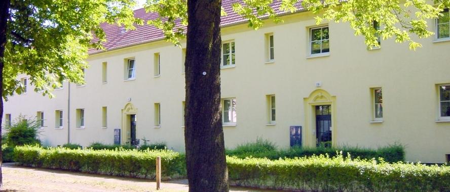Titelbild Walzwerksiedlung 2-stöckiges Wohnhaus mit mehreren Eingängen an einem begrünten Weg