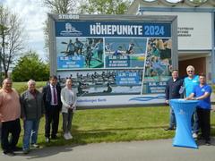 OB und Sportler vor dem Plakat