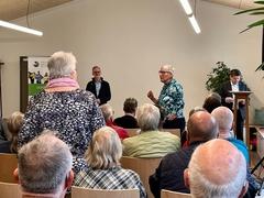 Blick in einem Raum mit Menschen auf Stühlen.